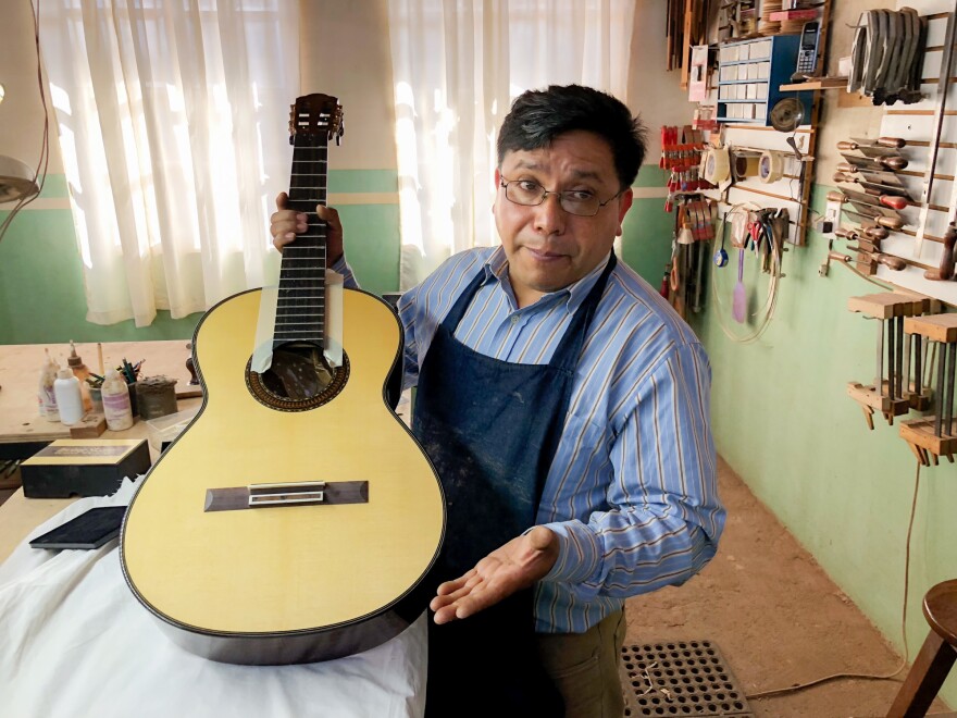 Master guitar maker Arnulfo Rubio Orozco holds up a recent project. It took him a month to craft this guitar with pearl accents and wood from southern Mexico.