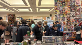 Saratoga Comic Con attendees browsing rows of comic books, vintage video games, and custom dice