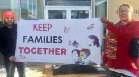 A man and a woman hold a sign reading Keep Families Together