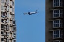 A Cathay Pacific airliner flies past residential buildings as it prepares to land at the Beijing Capital International Airport, in Beijing, Monday, Dec. 1, 2025. (AP Photo/Andy Wong)