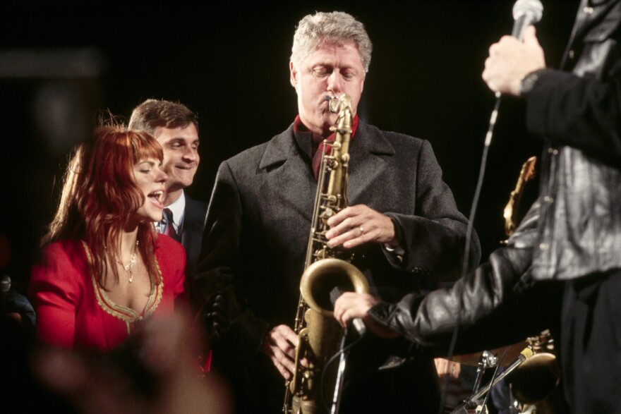 Democratic presidential candidate Bill Clinton plays saxophone in 1992 while some of his supporters sing and dance.