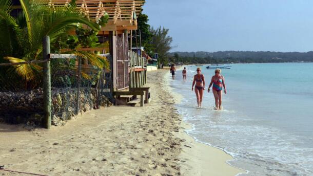 Sunbathers walk along a badly eroding patch of resort-lined crescent beach in Negril in western Jamaica. (David McFadden/AP)