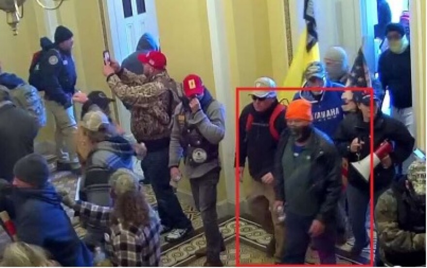 The FBI says this surveillance photo shows Tennessee resident Michael Timbrook (orange cap in the red box) can be observed walking into a room designated for the use of an employee of Congress during the Jan. 6, 2021, breach of the U.S. Capitol Building.