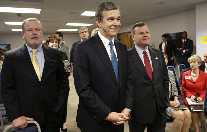 In this May 1, 2018, file photo, from left, Senate leader Phil Berger, North Carolina Gov. Roy Cooper and House Speaker Tim Moore pause prior to a news conference in Raleigh, N.C.