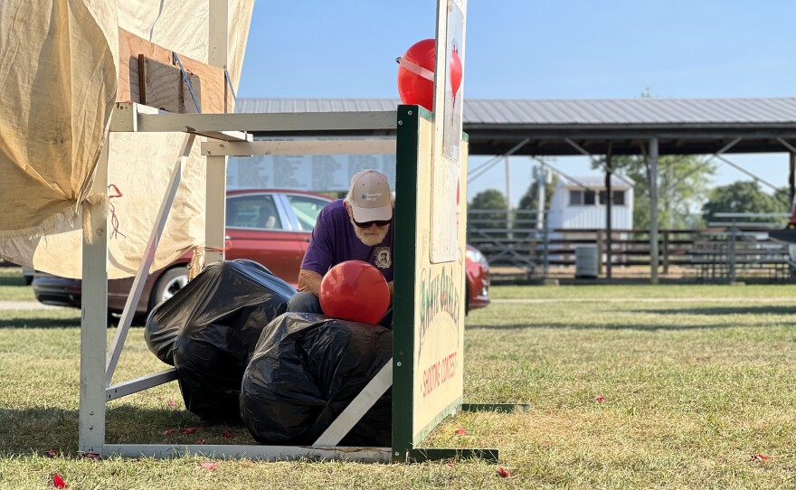 A volunteer waits with a bag of red balloons to replace the ones that are shot.