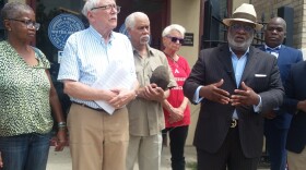 Bishop Tom Watson, in hat, leads a prayer vigil to stop the Sewerage and Water Board from cutting service to customers owing on water bills.