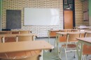 Desks sit in rows in front of a whiteboard and blackboard.