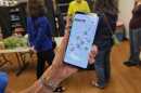 A hand holding a smart phone with the Last Mile Food Rescue app, which shows a map of Cincinnati with green icons indicating where 