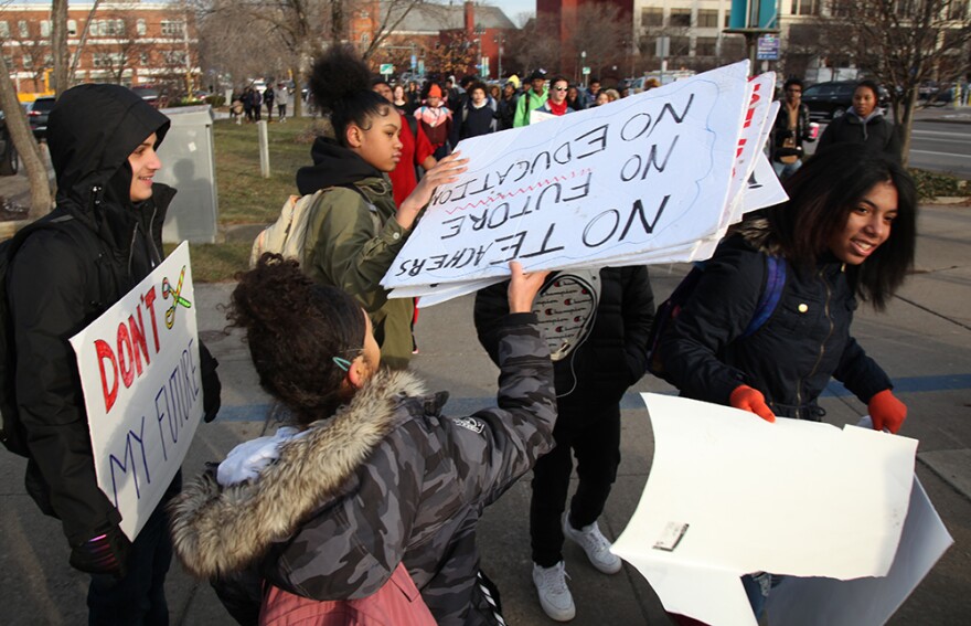 Madison Smith, a senior at East High School, hands out signs to students who walked out of classes Monday morning to protest in front of the Rochester City School District offices.