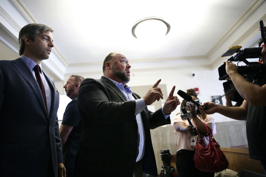 Alex Jones talks to media during a midday break during the trial at the Travis County Courthouse in Austin, Texas, Tuesday, July 26, 2022. An attorney for the parents of one of the children who were killed in the Sandy Hook Elementary School shooting told jurors that Jones repeatedly “lied and attacked the parents of murdered children” when he told his Infowars audience that the 2012 attack was a hoax. Attorney Mark Bankston said during his opening statement to determine damages against Jones that Jones created a “massive campaign of lies” and recruited “wild extremists from the fringes of the internet ... who were as cruel as Mr. Jones wanted them to be" to the victims' families. Jones later blasted the case, calling it a “show trial” and an assault on the First Amendment.