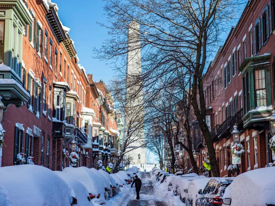 A person shovels out homes and cars near the Bunker Hill Monument in Boston, Massachusetts, on January 30, 2022. - Blinding snow whipped up by powerful winds pummeled the eastern United States into the early hours of January 30, as one of the strongest winter storms in years triggered transport chaos and power outages across a region of some 70 million people. (Photo by JOSEPH PREZIOSO / AFP) (Photo by JOSEPH PREZIOSO/AFP via Getty Images)
