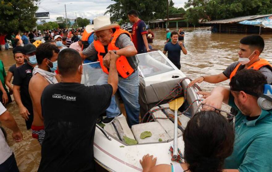 A resident is helped off a boat after he was rescued from a flooded area in the neighborhood of Planeta, Honduras, Thursday, Nov. 5, 2020. The storm that hit Nicaragua as a Category 4 hurricane on Tuesday had become more of a vast tropical rainstorm, but it was advancing so slowly and dumping so much rain that much of Central America remained on high alert.