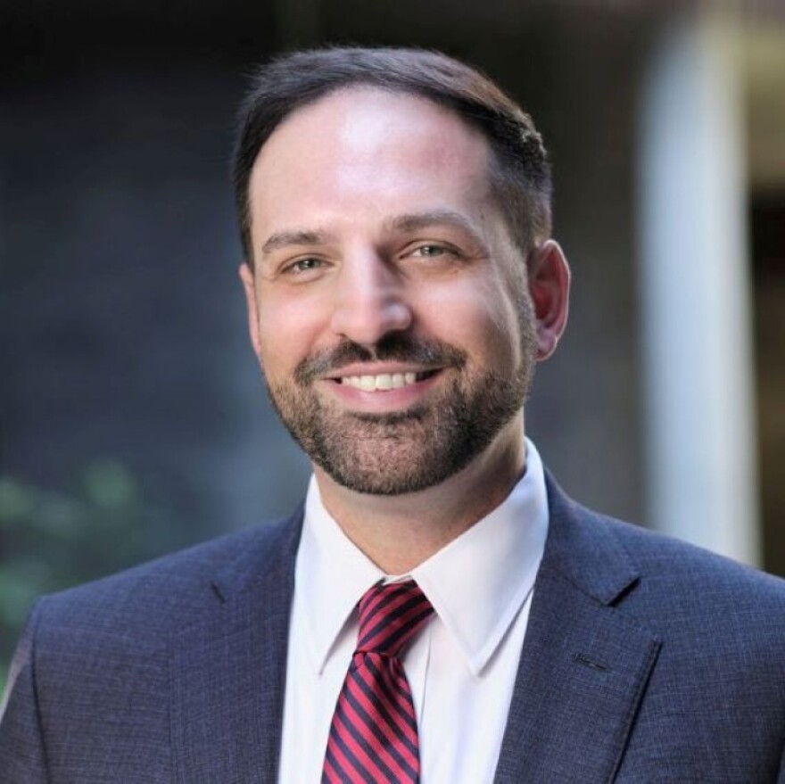 Christopher Griffin is a professor at the University of Arizona's James E. Rogers College of Law. In this photo he is wearing a suit and tie, but shown from the chest up. He is looking in the camera's direction and smiling.