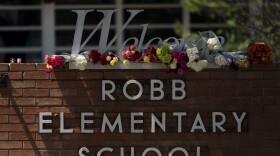 Flowers are placed around a welcome sign outside Robb Elementary School in Uvalde, Texas, Wednesday, May 25, 2022, to honor the victims killed in Tuesday's shooting at the school.