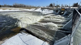 Water rushes through the spillway of a dam into an overflowing dam pool.