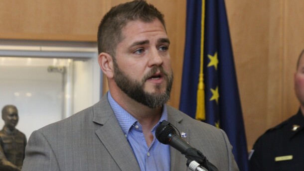 man with brown hair and beard speaks into microphone