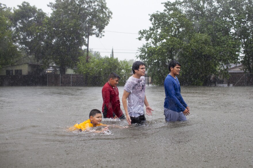 Kids walk — and swim — in the floodwaters in a Houston neighborhood as the rain continues to pour down.