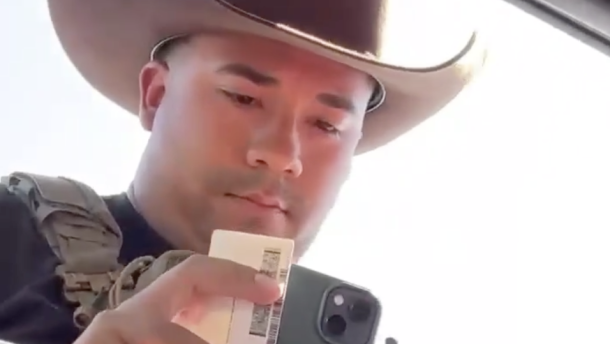 An unidentified Immigration and Customs Enforcement officer examines the driver's license of Dodge City, Kansas, resident Guadalupe Navarrete on Sept. 23, 2026. Navarrete was driving with her father Frank Duran. They were not detained.