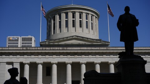 a statue is silhouetted in front of a columned building