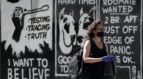 A woman with a face mask walks by a mural by contemporary artist Stephen Powers, also known as ESPO in New York.