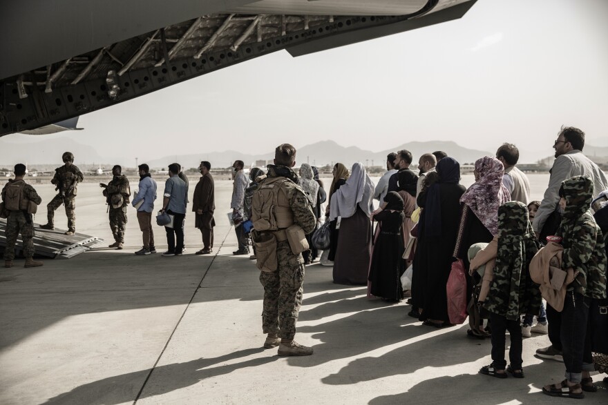 FILE - In this image provided by the U.S. Marine Corps, evacuees wait to board a Boeing C-17 Globemaster III during an evacuation at Hamid Karzai International Airport in Kabul, Afghanistan, Monday, Aug. 30. 2021. (Staff Sgt. Victor Mancilla/U.S. Marine Corps via AP, File)