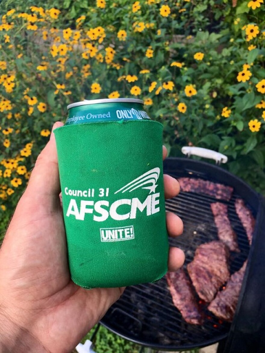 Man holding a beer in an AFCME coozi