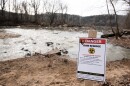 A warning sign is seen at the sight of a massive pipe rupture, as sewage flows into the Potomac River, right, in Glen Echo, Md., Jan. 23, 2026.