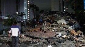 People walk amid debris after an earthquake in Caracas, Venezuela, Wednesday, June 24.