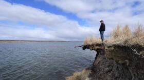 Tribal elder Warren Jones stands on the edge of climate change erosion caused by melting permafrost tundra and the disappearance of sea ice which formed a protective barrier, as it threatens houses from the Yupik Eskimo village of Quinhagak on the Yukon Delta in Alaska. (Mark Ralston/AFP via Getty Images)