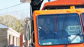 A St. Louis city refuse collector collects an alley container full of recycling.