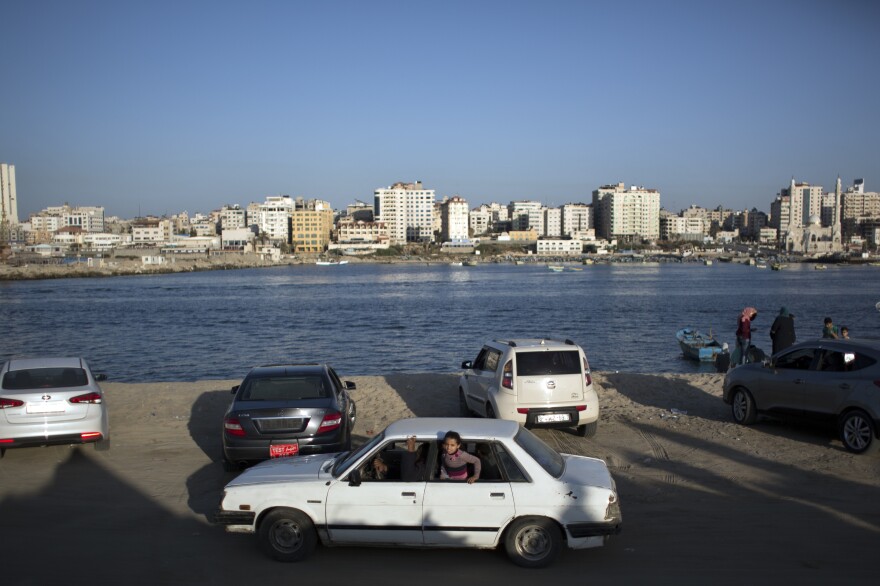 A girl appears from the window of a car driving along the beach in Gaza City.