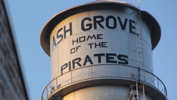 A water tower in the city of Ash Grove, displaying the name of the city and the name of the local school district's mascot.