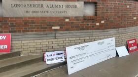 Protesters set signs down outside the Longaberger Alumni House at 2200 Olentangy River Rd., where the OSU Board of Trustees meet, after Thursday's meeting adjourned.