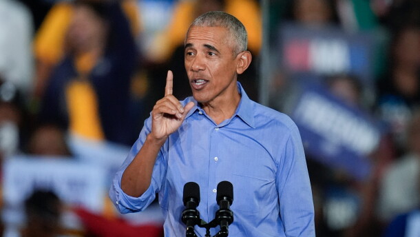 Former President Barack Obama speaks into a microphone on a podium at a rally