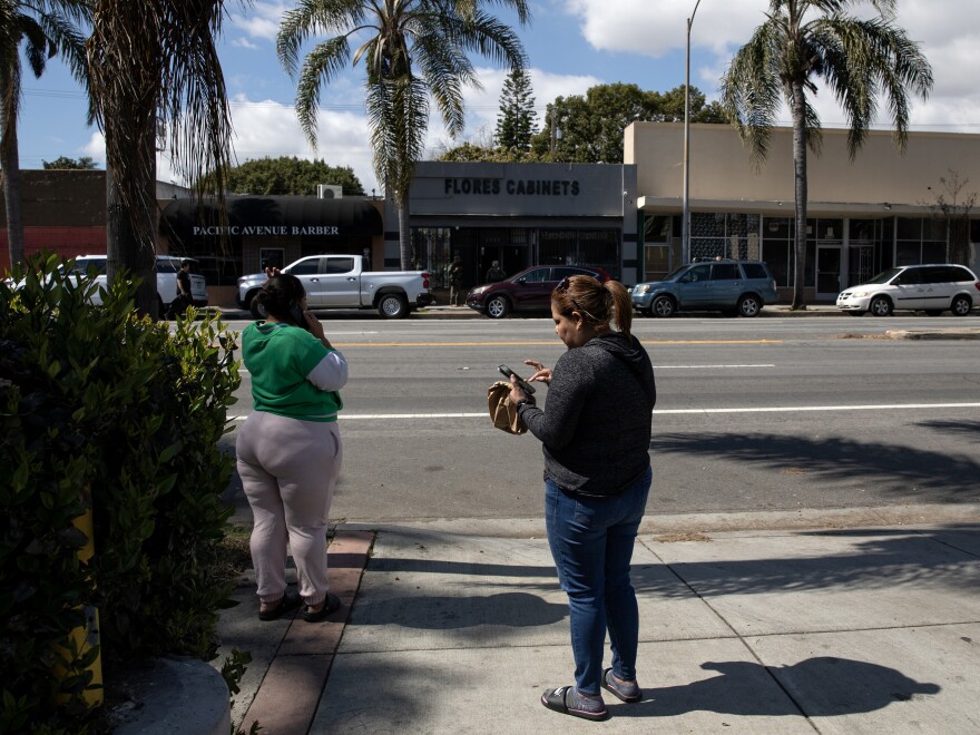 Passersby watch as California Department of Cannabis Control detectives, with support of Long Beach law enforcement, serve a search warrant on an unlicensed dispensary in Long Beach, Calif., on March 5, 2024. Like many unlicensed cannabis stores, this one is unmarked and still has signage from a previous business. Photo by Alisha Jucevic for NPR