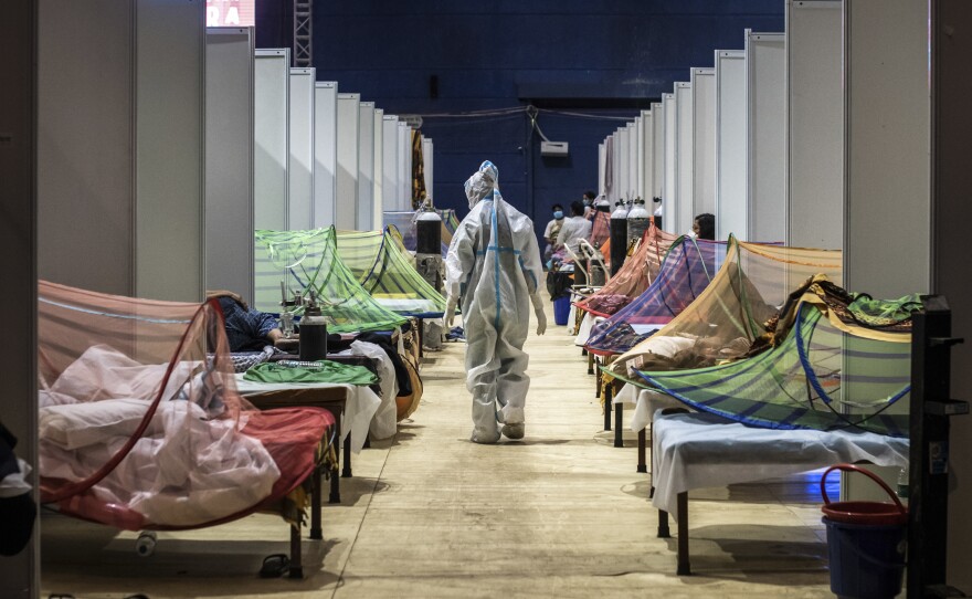 A medical worker observes COVID-19 patients in a sports stadium converted into a care facility. At the peak of the pandemic in India, there were over 400,000 cases — and 4,500 deaths — a day. Numbers are now starting to decline.