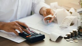 Man calculate domestic bills at home. Man using a calculator checking balance and costs at modern office.Business people doing paperwork for paying taxes.Expenses, account, taxes concept