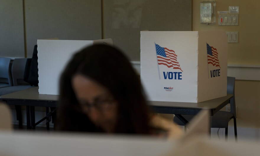 A voter in the foreground casts her ballot during the Republican primary election in Wilson, Wyo., on Aug. 16.