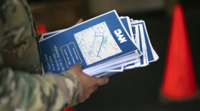 A military member carries flyers for asylum seeking migrants as they arrive to the Roosevelt Hotel in New York.