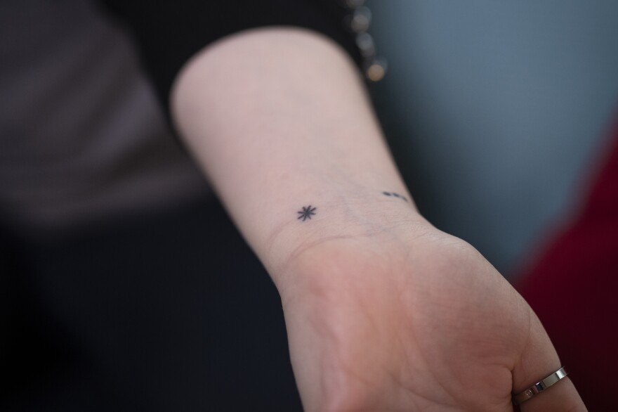 Heather Woock shows the asterisk tattoo she got with some of her half-siblings to represent the mark Donald Cline would make on their mothers' medical charts to note he used his own sperm for the procedure.