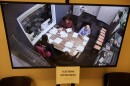 A photo of a television monitor which shows people counting ballots.