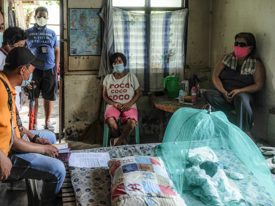 Members of the Bambang health unit question Jessa Tayombong (center) about the home birth of her daughter, Josie, on July 14, which goes against government policy. At right is neighbor Jelina Campoy, who assisted with the birth.