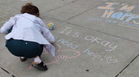  A student at Vestal High School chalks an inspirational message on the sidewalk outside the school as part of a mental health activity last fall.