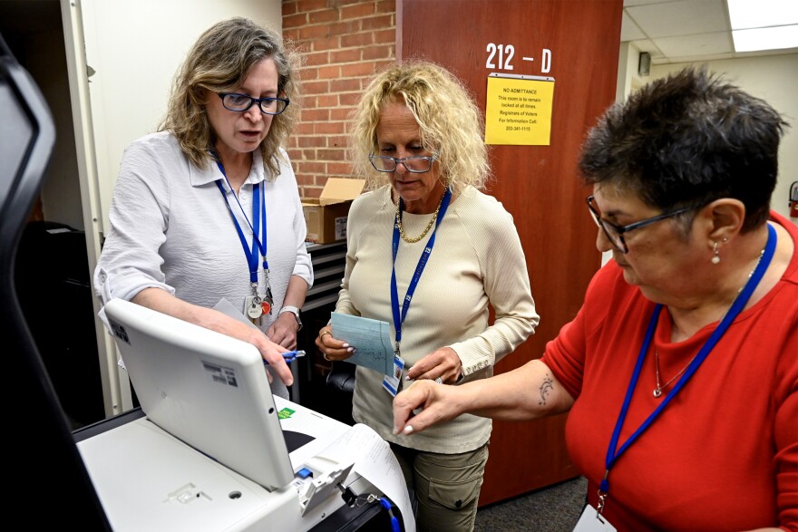 Left to right: Democratic Deputy Registrar of Voters Sharon Fiarman, Democratic Registrar of Voters Deborah Greenberg, and Republican Registrar of Voters Francesca Signore, test a tabulator, a machine that counts paper ballots at Westport Town Hall on July 21, 2026.