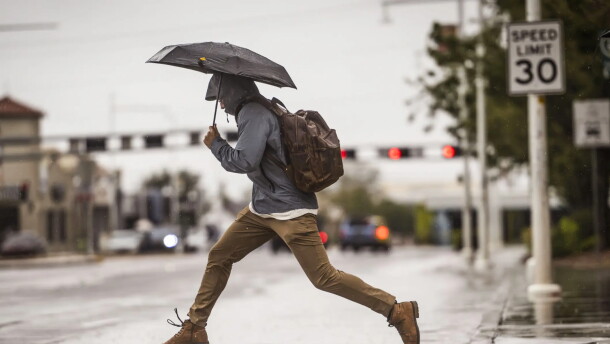 A man leaps over a large puddle on Central Avenue near the University of New Mexico on Wednesday.