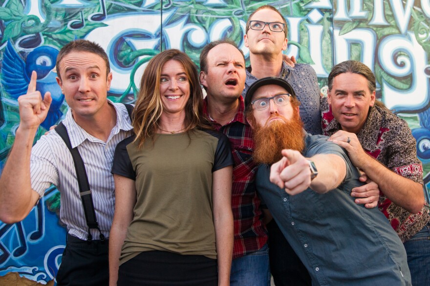 A silly group shot of the band members in front of a mural. 