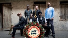 The Preservation Hall Jazz Band is posed behind a Christmas wreath.