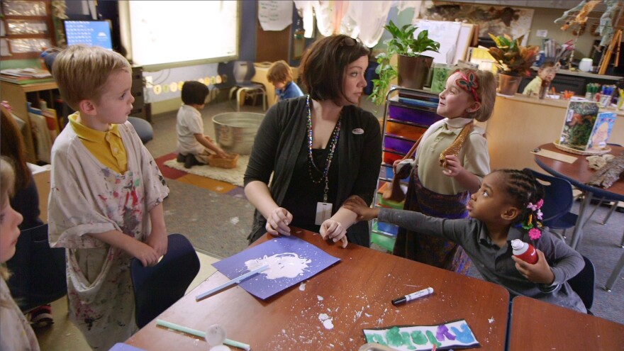 Teacher surrounded by pre-k students working at a table. 