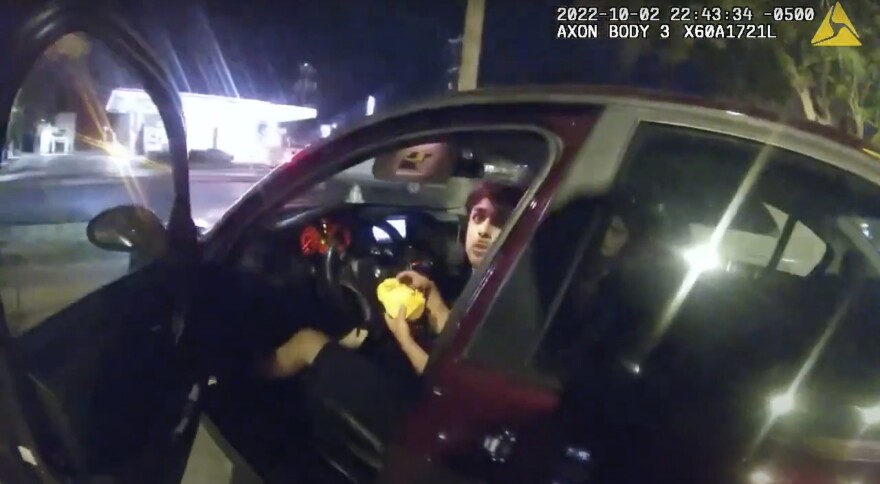 FILE - In this image taken from Sunday, Oct. 2, 2022, police body camera video and released by the San Antonio Police Department, Erik Cantu looks toward San Antonio Police Officer James Brennand while holding a hamburger in a fast food restaurant parking lot as the officer opens the car door in San Antonio, Texas.