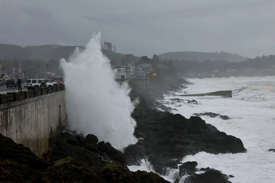 Waves crash into a concrete seawall.